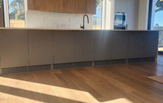 A kitchen with a spacious island and wooden floor. Custom ducted install enhances the overall appeal.