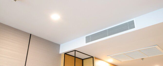 Duct air conditioner for home or office. Ceiling mounted cassette type air conditioner and modern lamp light on white ceiling.