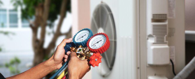 Technician holding manifold gauge measuring tool on fan for check pump filling home air conditioner and checking refrigerant and maintenance heat fix repair and clean outdoor air compressor unit.